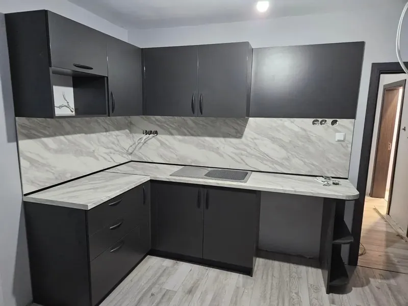 L-shaped kitchen in anthracite and light wood with a marble-effect worktop and splashback