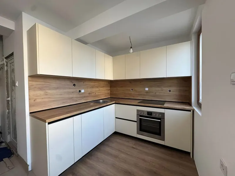 Finished L-shaped white kitchen with a wood-effect worktop and splashback