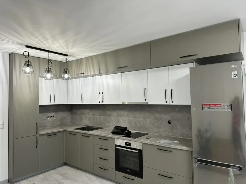 Sage and white L-shaped kitchen with stone-effect splashback