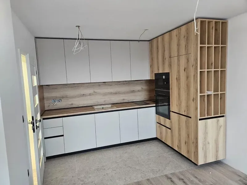 White kitchen with an oak tall unit, built-in oven and an integrated wine rack